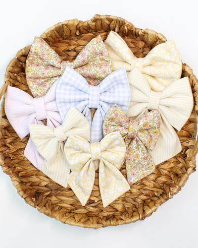 Assorted fabric collar bows in a wicker basket on a white background
